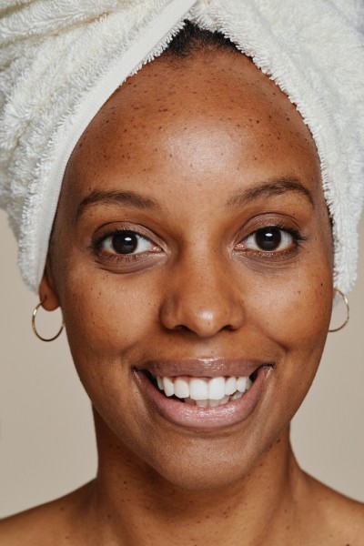 Vertical close up portrait of young African-American woman wearing head towel looking at camera